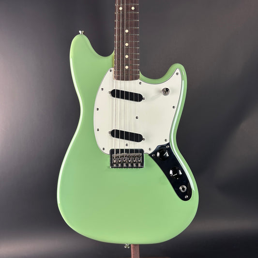 Green electric guitar on a dark gray background
