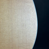 Close-up of a light natural wood grain surface with a curved edge against a dark navy background.