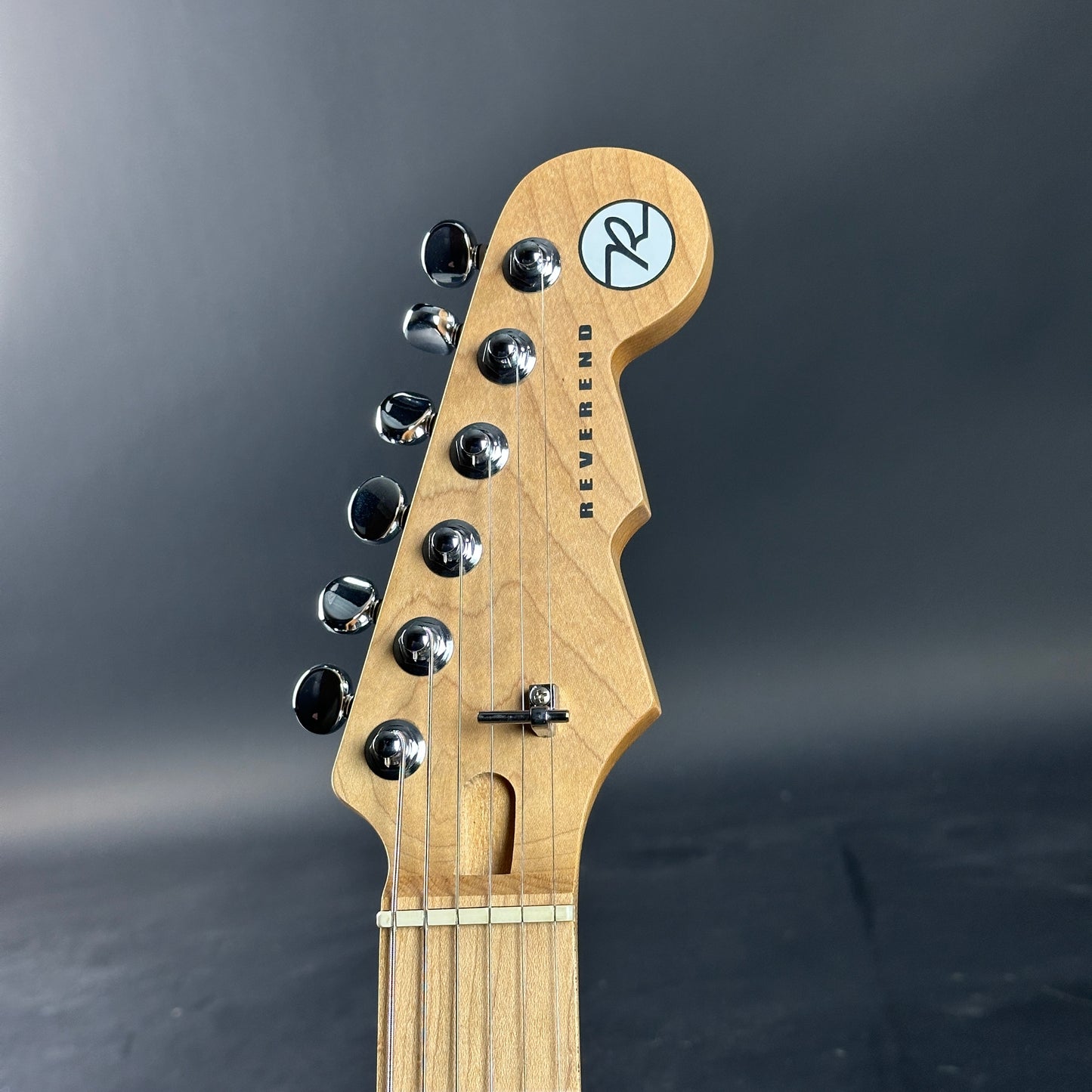 Guitar headstock with brand logo on a dark background