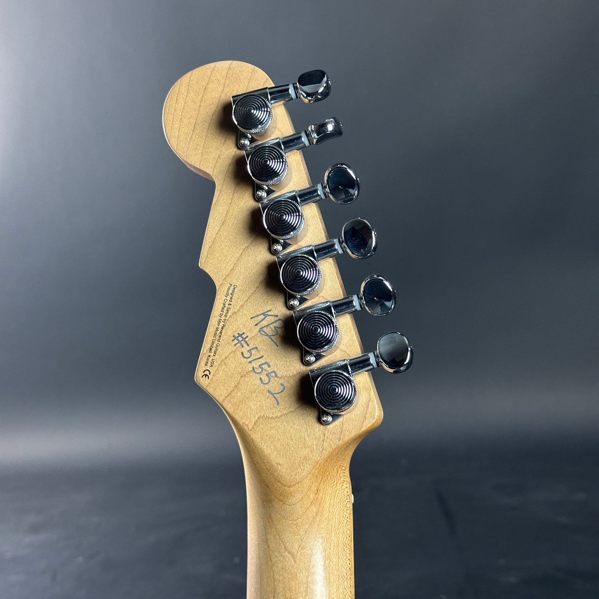 Guitar headstock with tuning pegs on a dark gray background