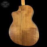 The back of a acoustic-electric guitar with a rich, warm brown wood finish and visible grain patterns, shown against a solid black background with a Tone Shop watermark in the top left corner.