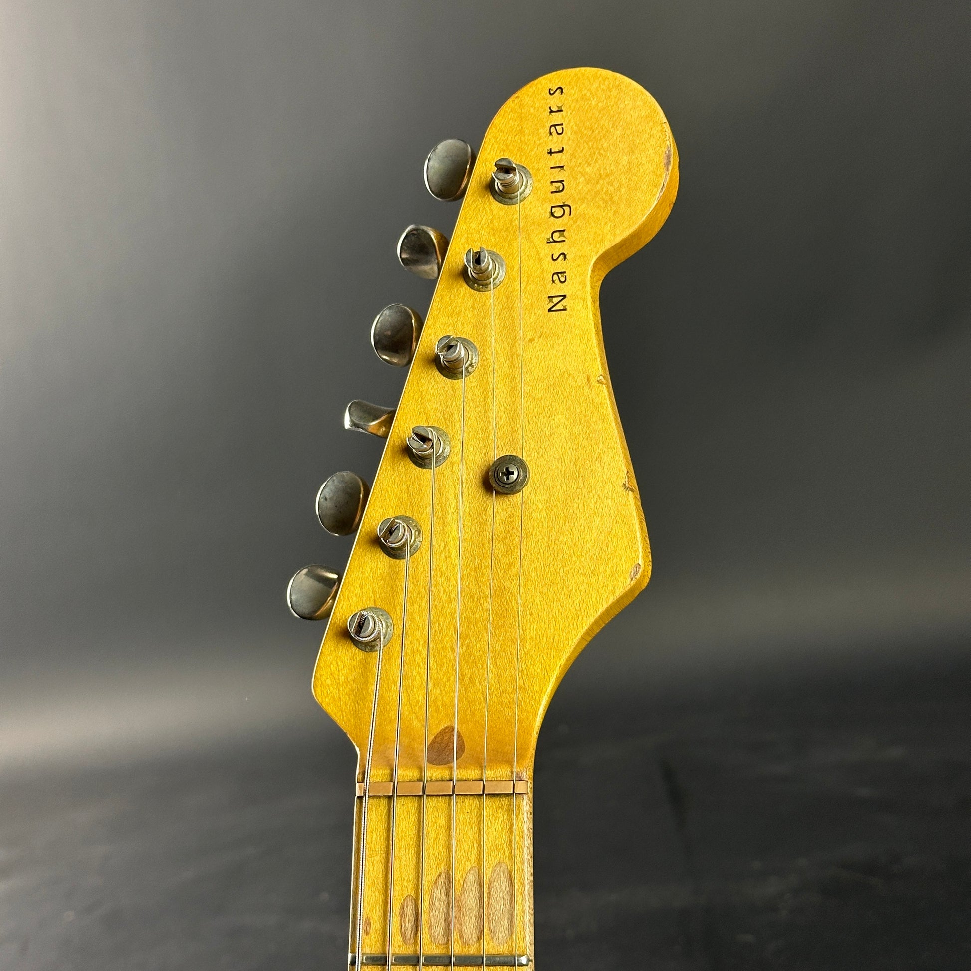 Guitar headstock with 'Nash Guitars' branding on a dark background