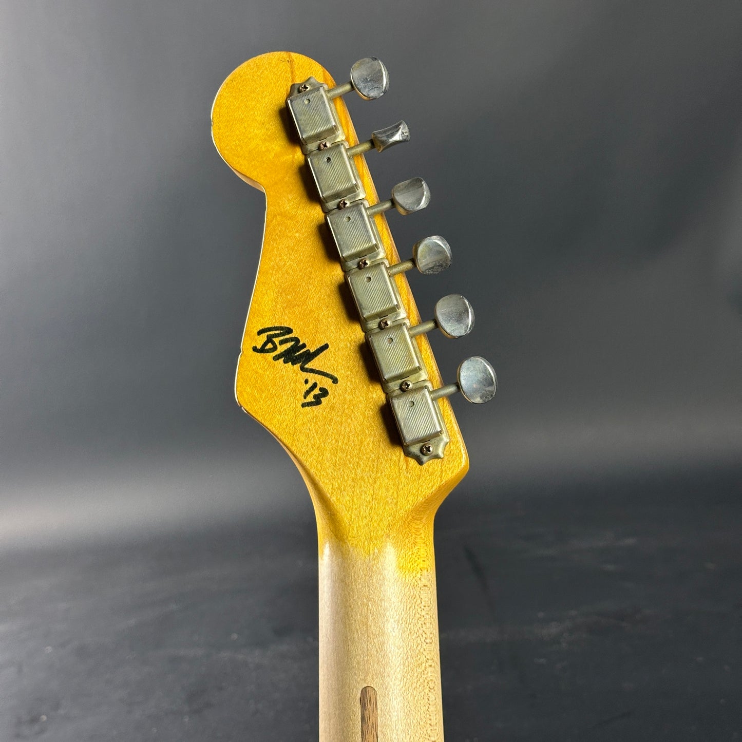 Guitar headstock with tuning pegs on a dark background