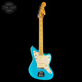 A turquoise blue electric guitar with a maple neck and headstock, featuring a cream pickguard and gold-toned hardware, shown against a solid black background with a Tone Shop watermark in the top left corner.