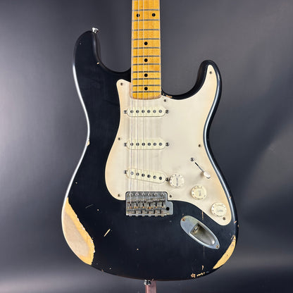 Black electric guitar with a worn finish on a dark background