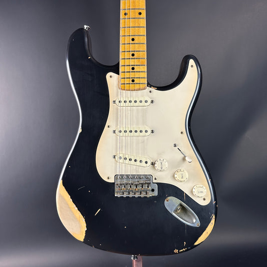 Black electric guitar with a worn finish on a dark background