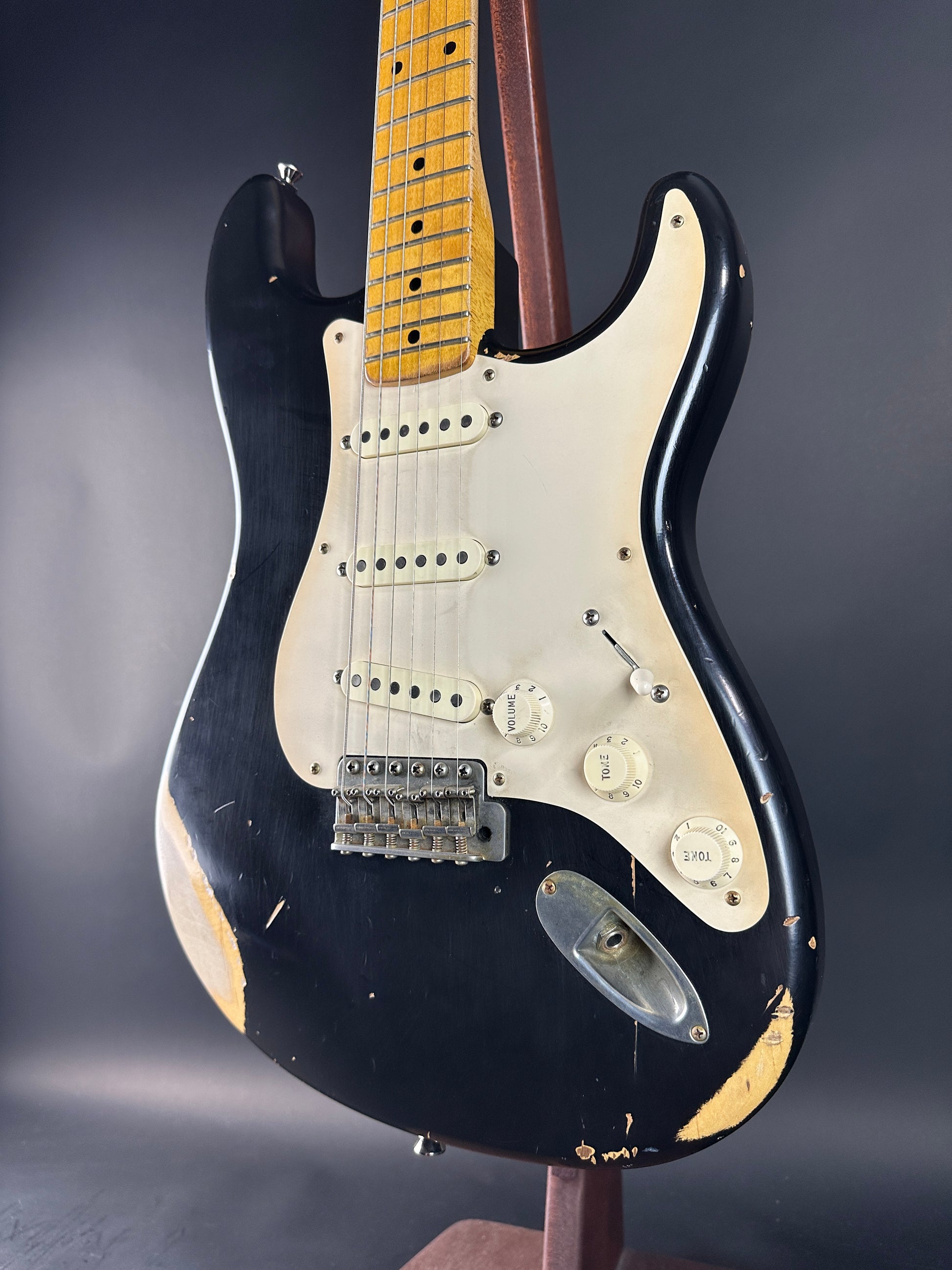 Black electric guitar with white pickguard on a dark background