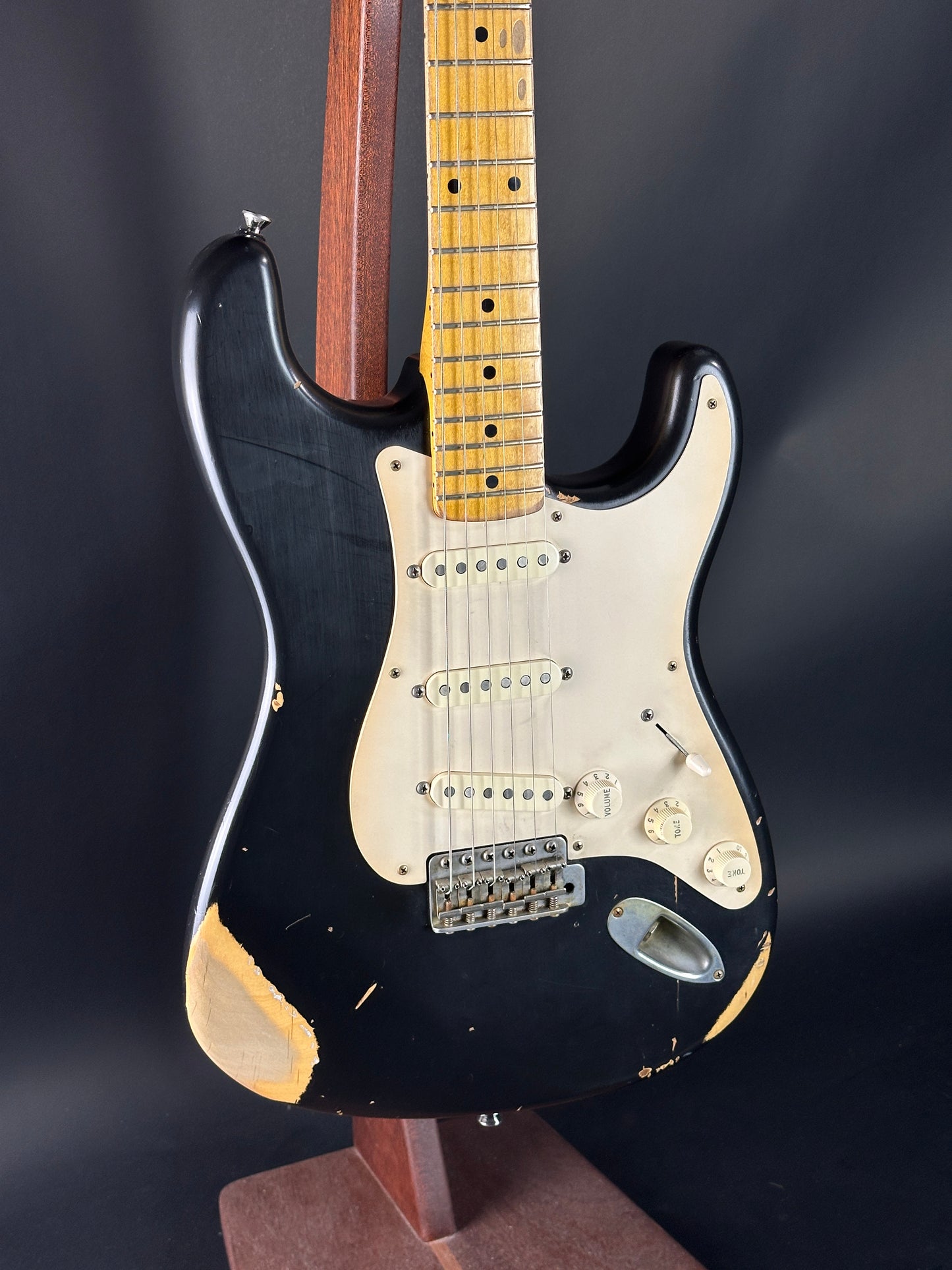 Black electric guitar with a worn finish on a dark background