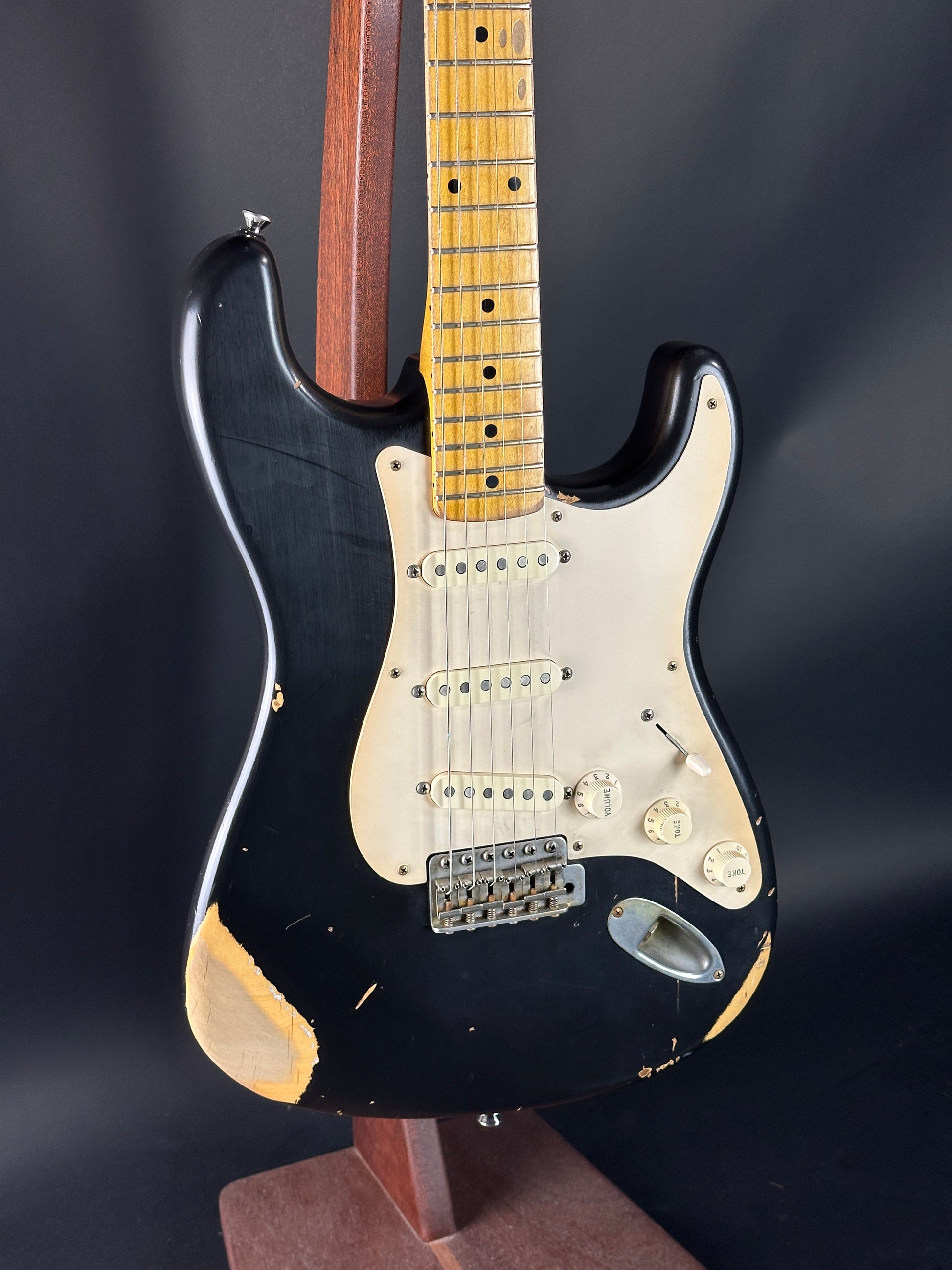 Black electric guitar with a worn finish on a dark background