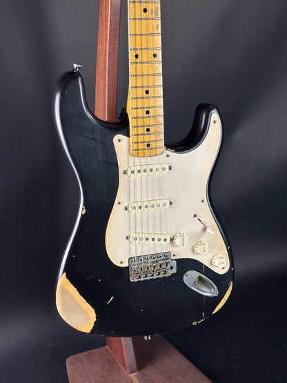 Black electric guitar with a worn finish on a dark background