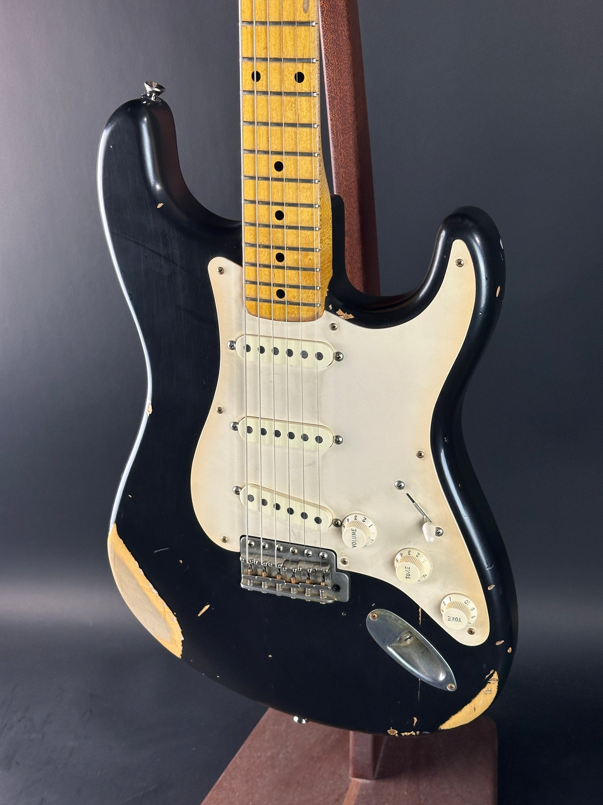 Black electric guitar with a white pickguard on a dark background