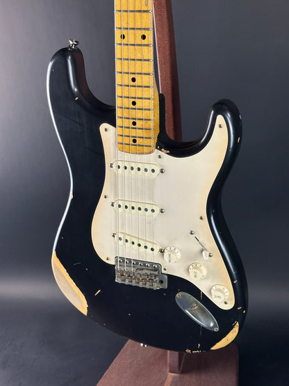 Black electric guitar with a white pickguard on a dark background