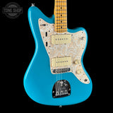 A turquoise blue Fender Stratocaster electric guitar with a cream paisley pickguard and maple neck, shown against a solid black background.