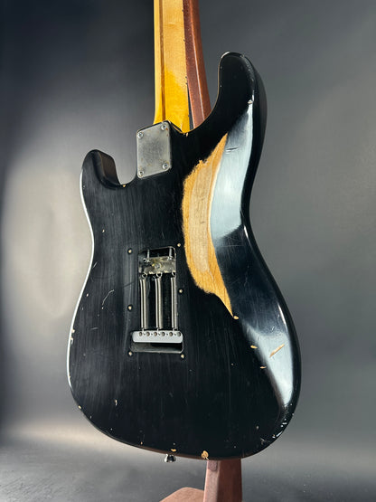 Close-up of a guitar's back with a black pickguard and wooden neck