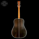 Acoustic guitar with a dark wood finish on a black background, featuring the Tone Shop logo.
