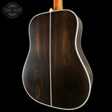 Back view of a wooden acoustic guitar with 'Tone Shop' logo.