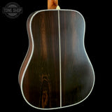 Back view of a wooden acoustic guitar with 'Tone Shop' logo.