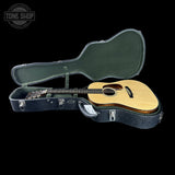 Acoustic guitar in a hard case with 'Tone Shop' logo in the corner.