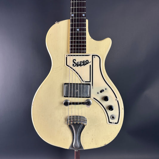 Beige electric guitar with Supro logo on a dark background