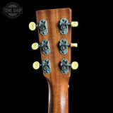 Close-up of the headstock of a wooden acoustic guitar, showing six tuning pegs with pale yellow knobs against a solid black background. A 'TONE SHOP' watermark is visible in the top-left corner.