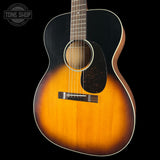 A vintage-style acoustic guitar with a natural sunburst finish, featuring a black pickguard and a white binding, shown against a solid black background.