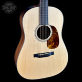 Acoustic guitar with a tortoiseshell pickguard on a black background, featuring the Tone Shop logo.