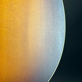 Close-up of a circular wooden surface with a warm golden-brown finish on the left and a darker black area on the right, separated by a thin light edge.