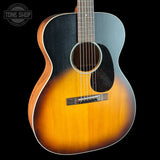 A classic acoustic guitar with a natural sunburst finish, featuring a black pickguard and a dark headstock, shown against a solid black background with a Tone Shop watermark in the upper left.