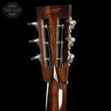 Close-up of a guitar headstock with tuning pegs on a black background, featuring the Tone Shop logo.