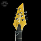 Close-up of a yellow electric guitar headstock with six silver tuning pegs and the Jackson brand name printed in white script, set against a solid black background.