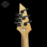 Close-up rear view of an electric guitar headstock in natural wood, showing six black tuning pegs with silver and black knobs, printed model text, and a Tone Shop watermark in the upper left against a black background.