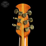 Close-up of a guitar headstock with tuning pegs on a black background, featuring the Tone Shop logo.