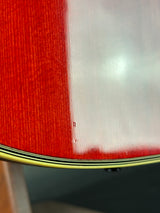 Close-up of a red guitar with a white pickguard and black pickguard
