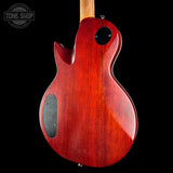 The back of a red electric guitar with a glossy cherry red finish, featuring a cutaway body shape, black pickups, and a light wood neck, shown against a black background.