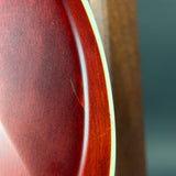 Extreme close-up of a glossy reddish-brown wooden surface with a curved edge and a vertical wood grain background.
