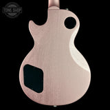 The back of a Gibson Les Paul Custom electric guitar in a textured rose gold finish, shown against a solid black background with a Tone Shop watermark in the top left corner.