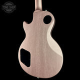 The back of an electric guitar with a natural wood finish, shown against a solid black background. A Tone Shop watermark is visible in the top-left corner.