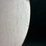 Close-up of a curved, metallic silver surface with a brushed texture and fine vertical grain, set against a solid black background.