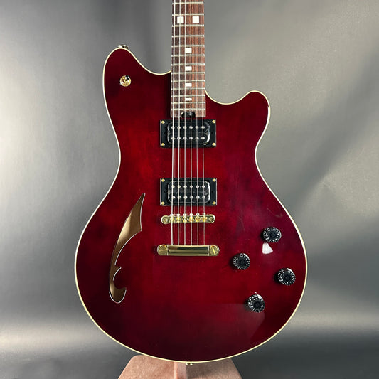 Red electric guitar held against a gray background