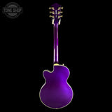 A purple electric guitar shown from the back against a solid black background, featuring gold tuning pegs and a white binding edge.