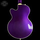 The back of a purple electric guitar with gold hardware and white binding, shown against a solid black background with a Tone Shop watermark in the top left corner.