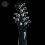 Close-up of a guitar headstock with tuning pegs on a black background, featuring the Tone Shop logo.