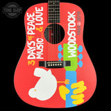 Woodstock-themed guitar with colorful design and text on a red background