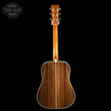 The back of an acoustic guitar with a glossy dark brown wood finish, shown against a solid black background. A Tone Shop watermark is visible in the top-left corner.