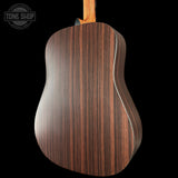 Back view of a wooden acoustic guitar with 'Tone Shop' logo.