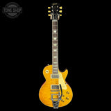 A Gibson Les Paul Custom electric guitar with a natural flamed maple top, black headstock, and gold hardware, shown against a solid black background with a Tone Shop watermark in the top-left corner.