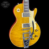 A Gibson Les Paul Custom electric guitar with a natural flame maple top, red body binding, and a silver Biggestripes tailpiece, shown against a solid black background.