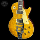 A Les Paul style electric guitar with a natural flame maple top, cream pickguard, gold hardware, and a black tremolo system, shown against a black background with a Tone Shop watermark.