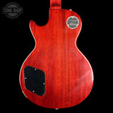 The back of a Gibson Les Paul Custom electric guitar in a vibrant red cherry finish, featuring a black pickguard and a silver chrome headstock badge, shown against a solid black background.