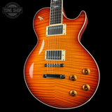 A classic electric guitar with a vibrant sunburst flame finish, featuring gold hardware and a black pickguard, shown against a solid black background with a Tone Shop watermark in the top left corner.